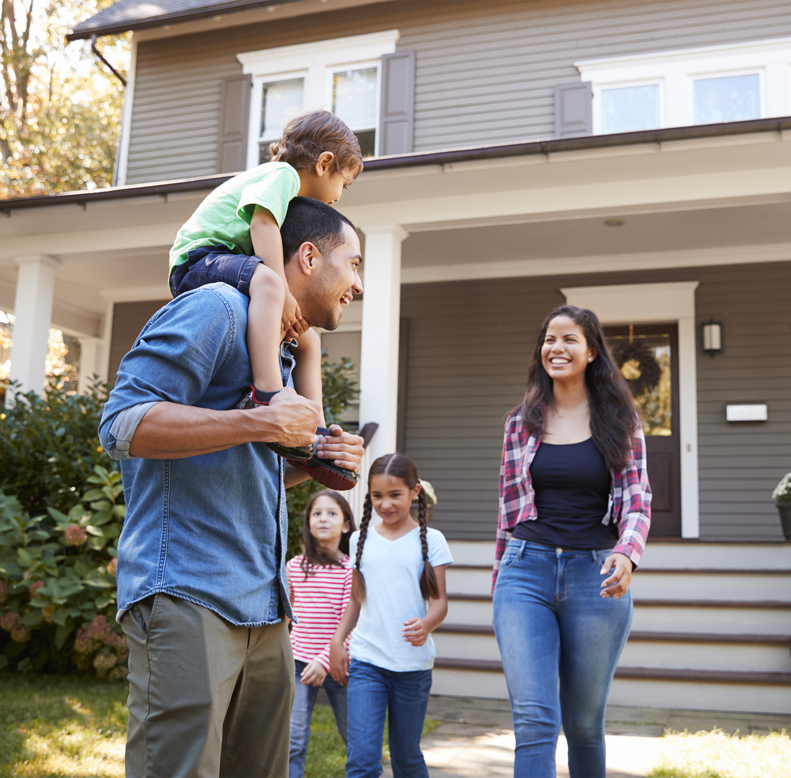 Une famille de trois enfants et deux parents sortant de leur maison